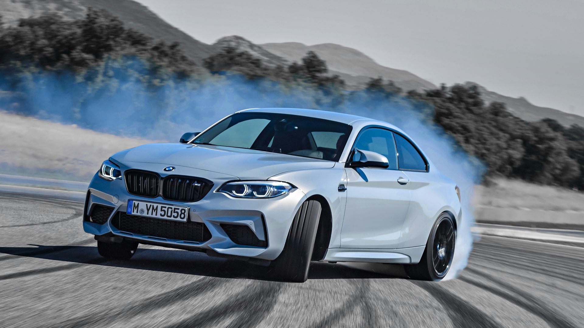 a white bmw car driving down a road