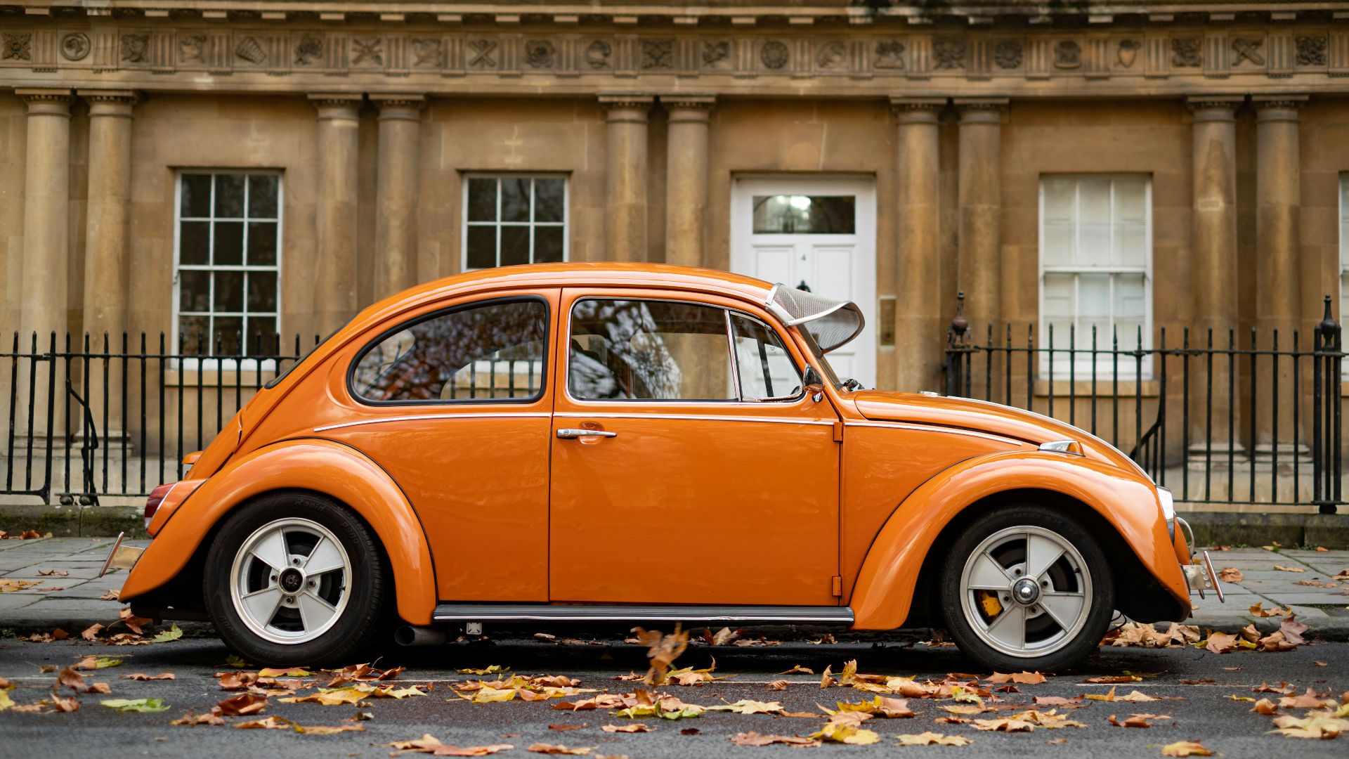 orange volkswagen beetle parked near building