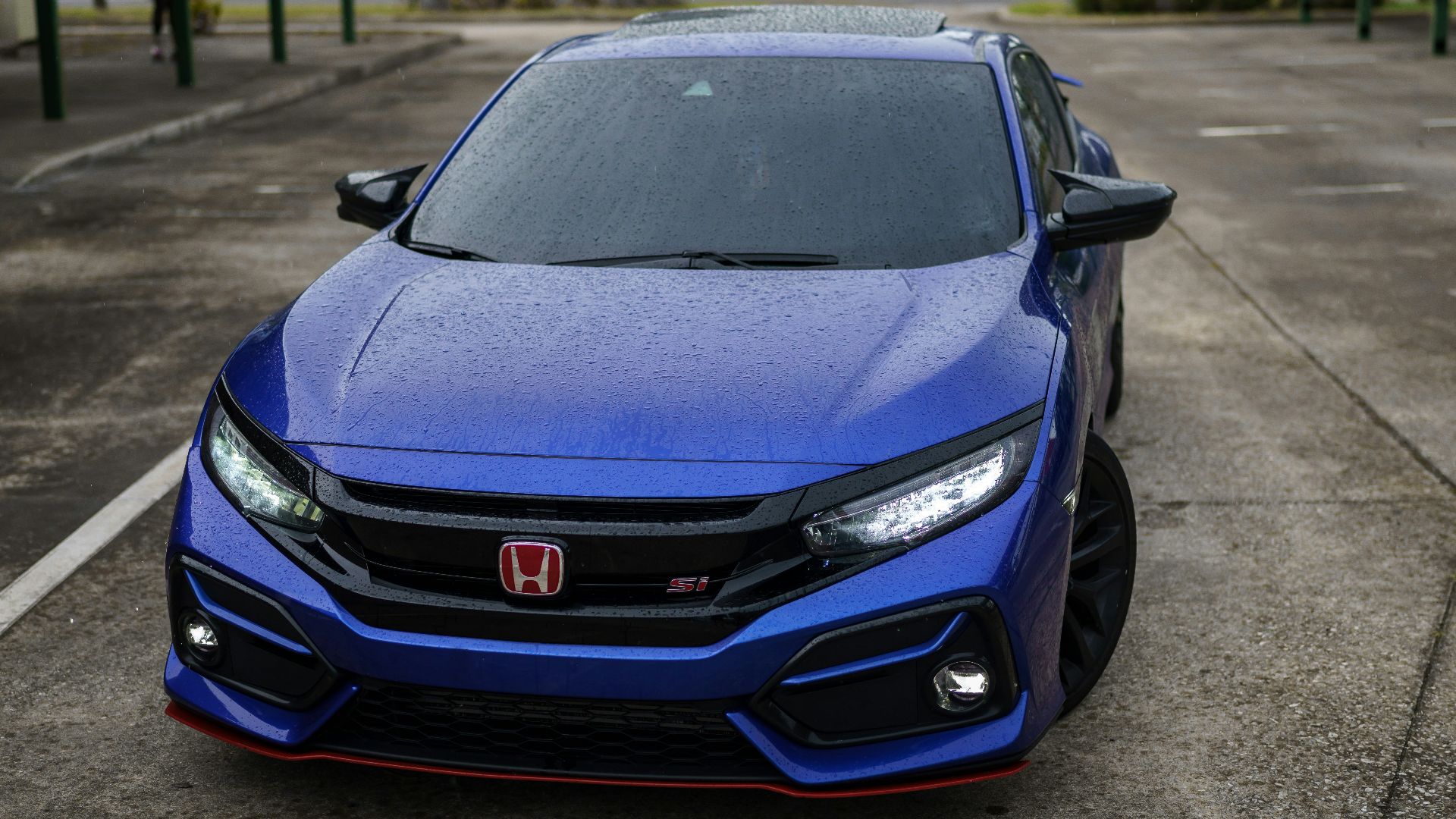 a blue sports car parked on a street with palm trees and a building