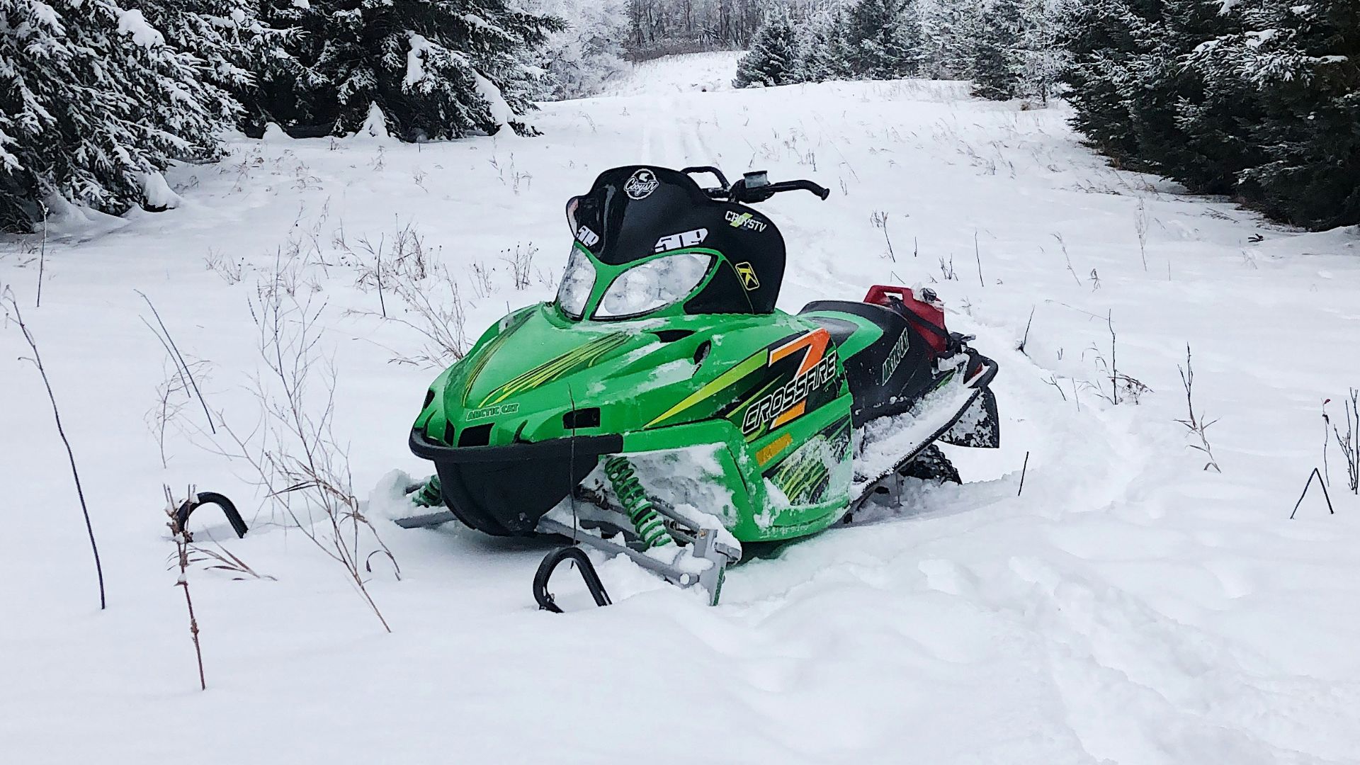 snowmobile on snow field by trees