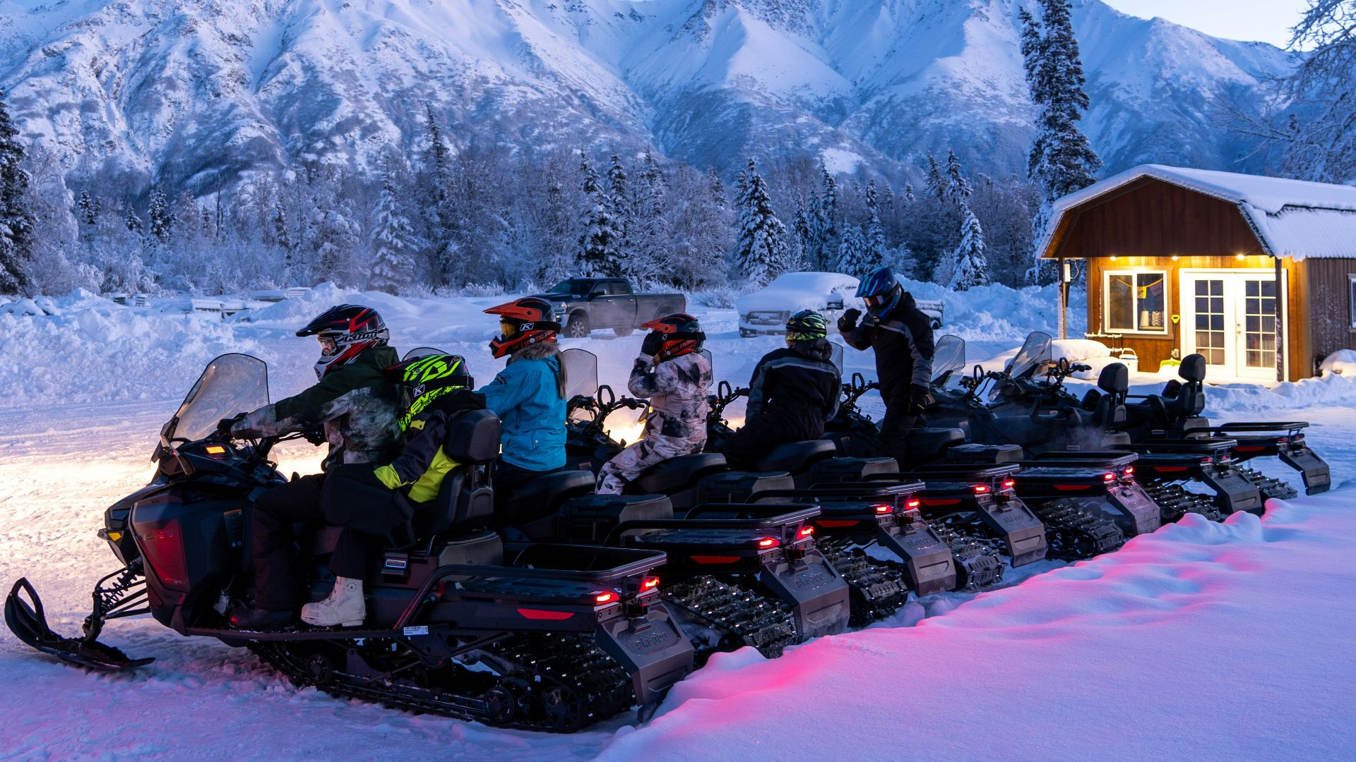 a group of people riding snowmobiles in the snow