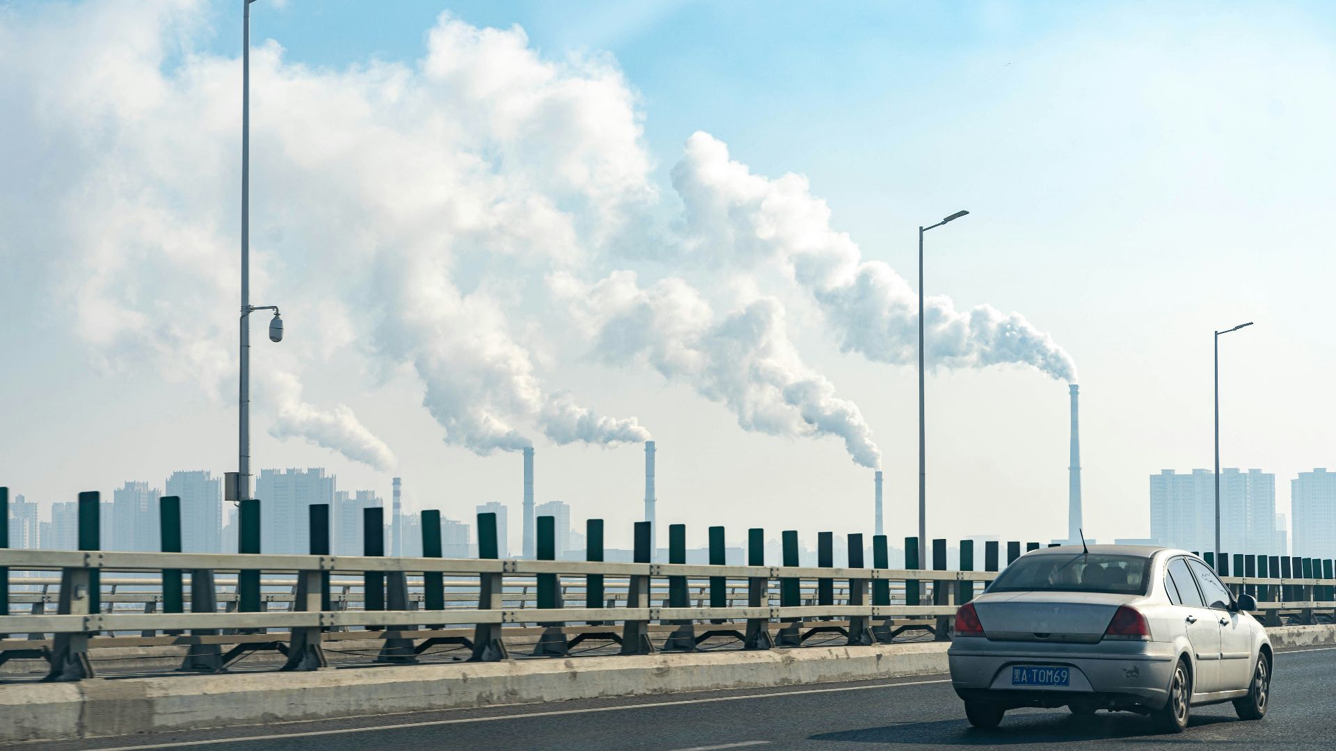 a car driving on a road with a large cloud of smoke behind it