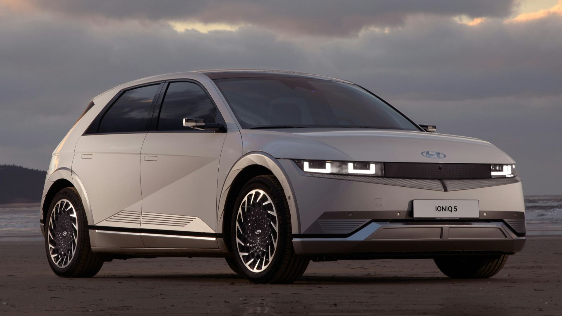 a white car parked on top of a sandy beach