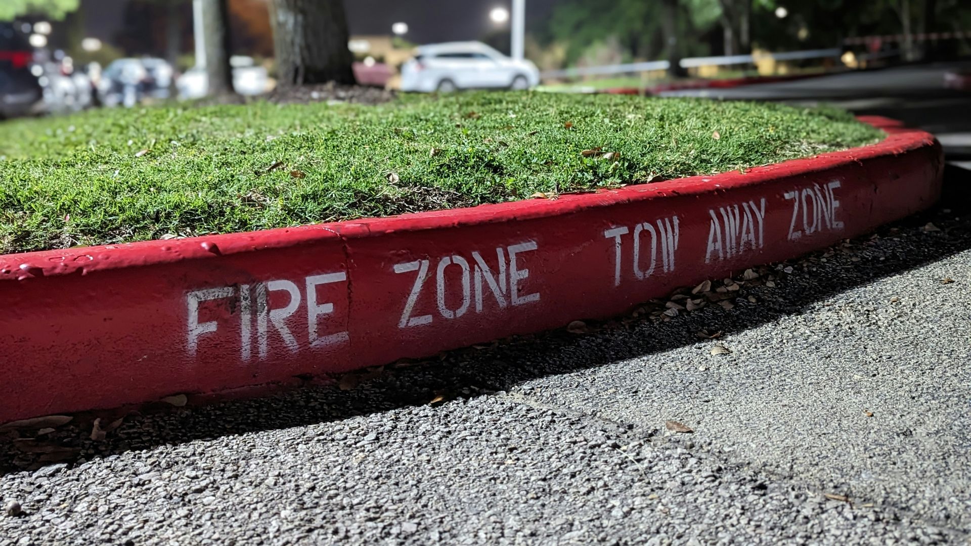 a red fire zone sign sitting on the side of a road