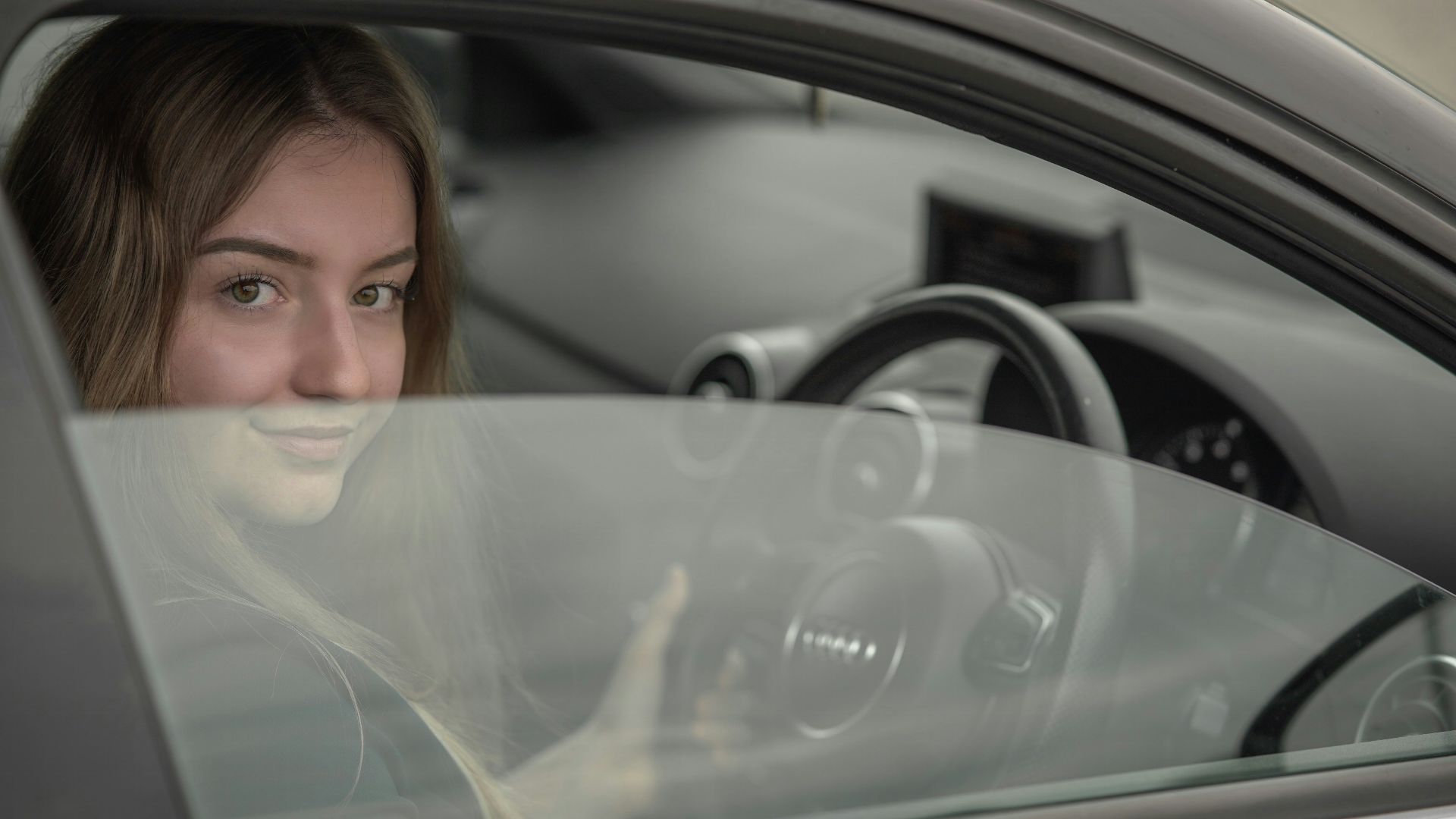 a woman sitting in a car holding a steering wheel