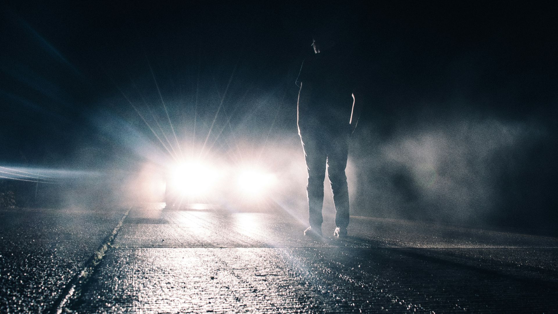man standing in front of lighted car