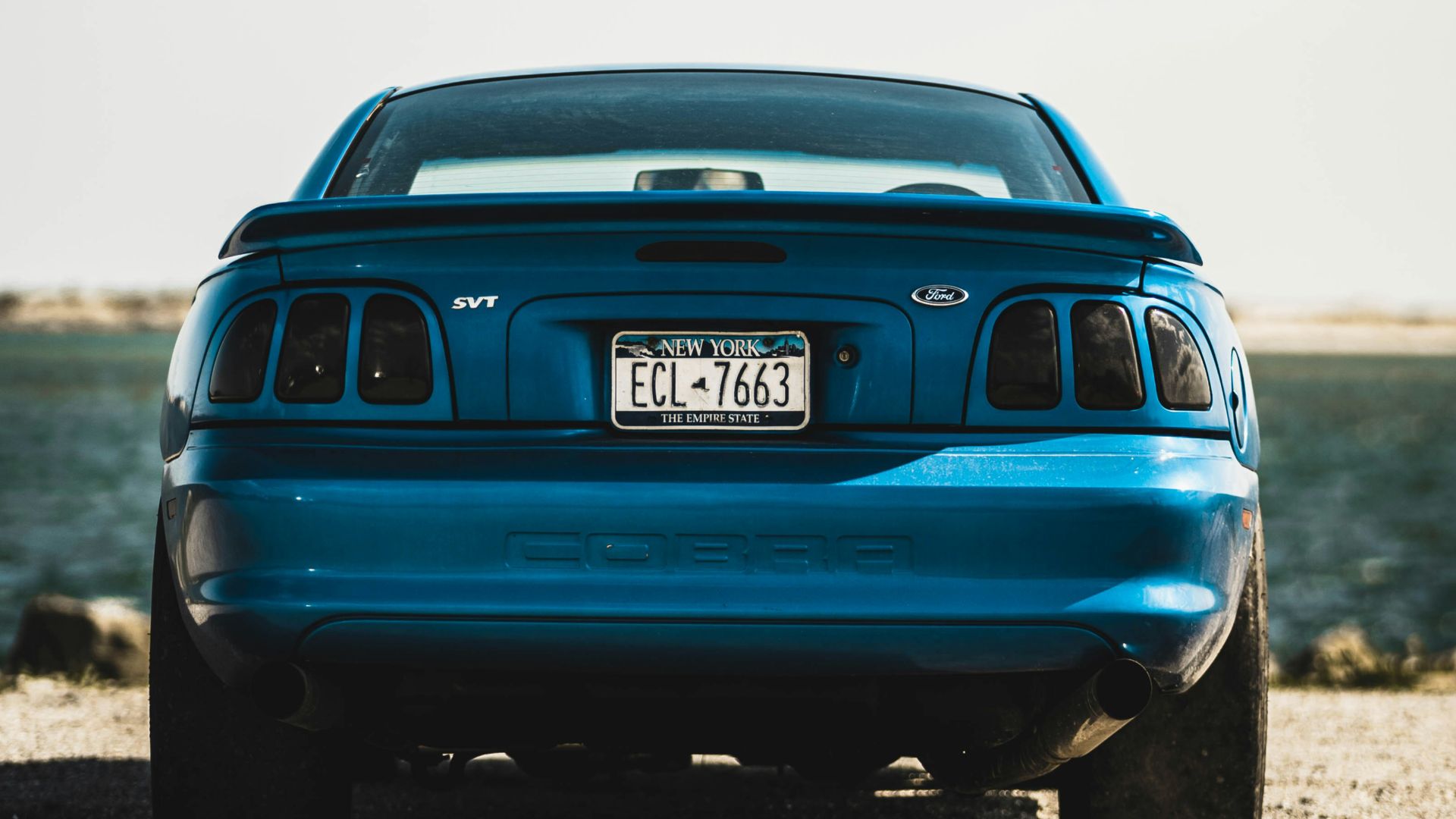 parked blue vehicle near body of water