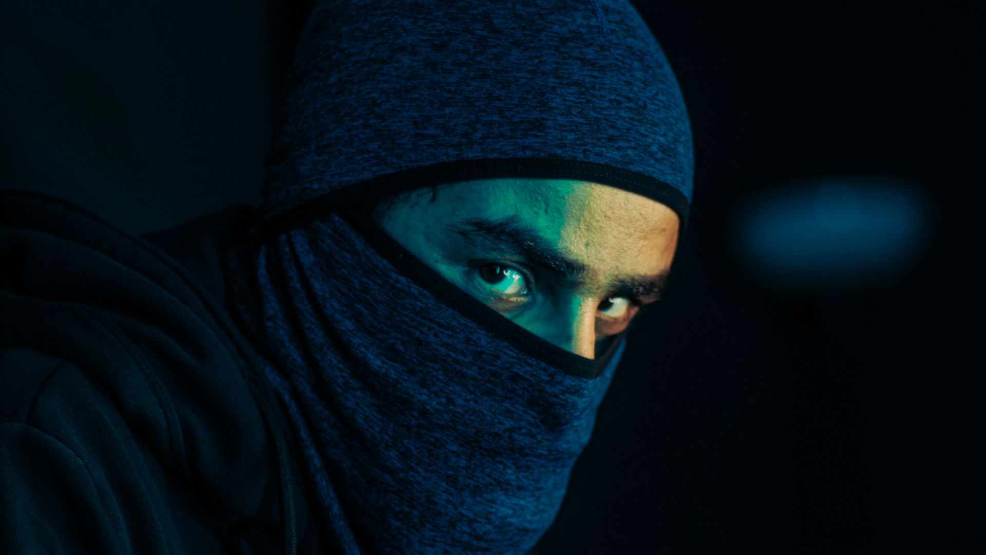 a man wearing a black hoodie and a blue mask