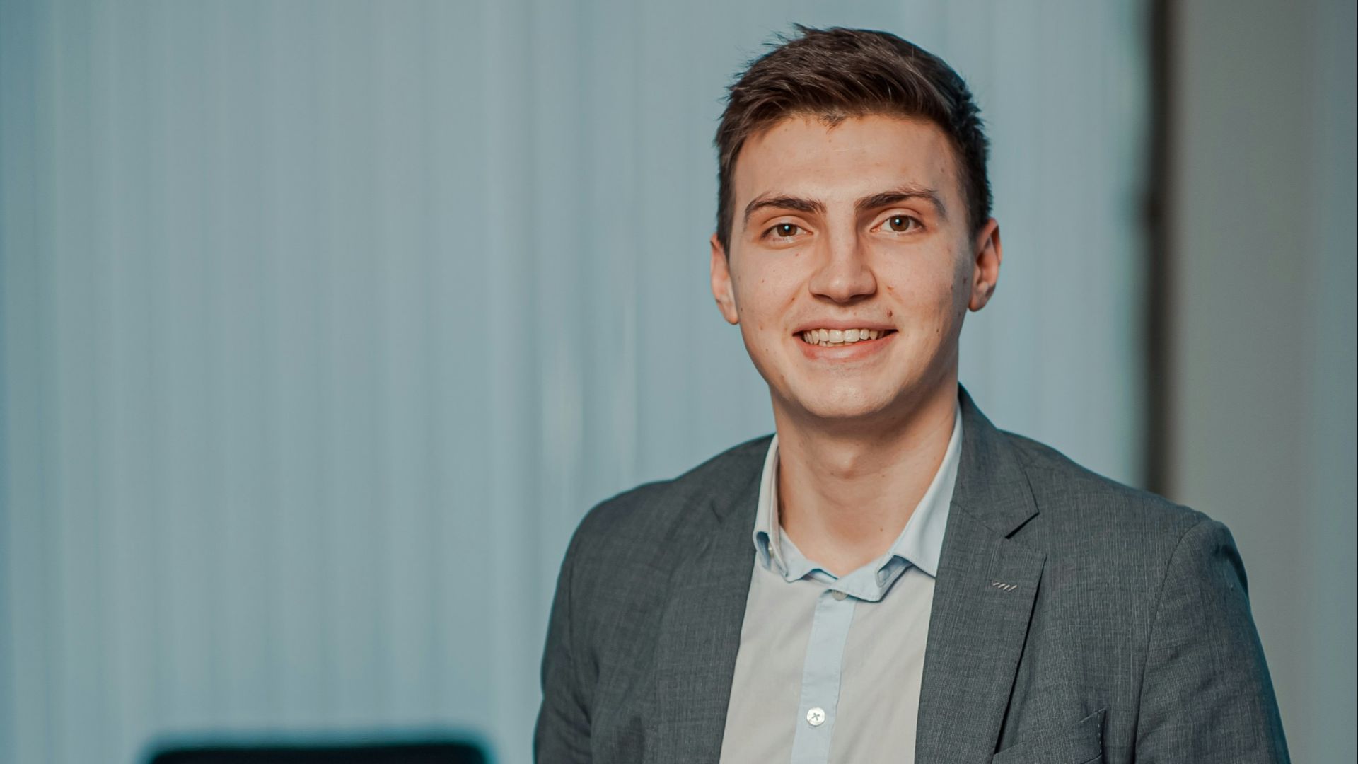 man in gray suit jacket smiling