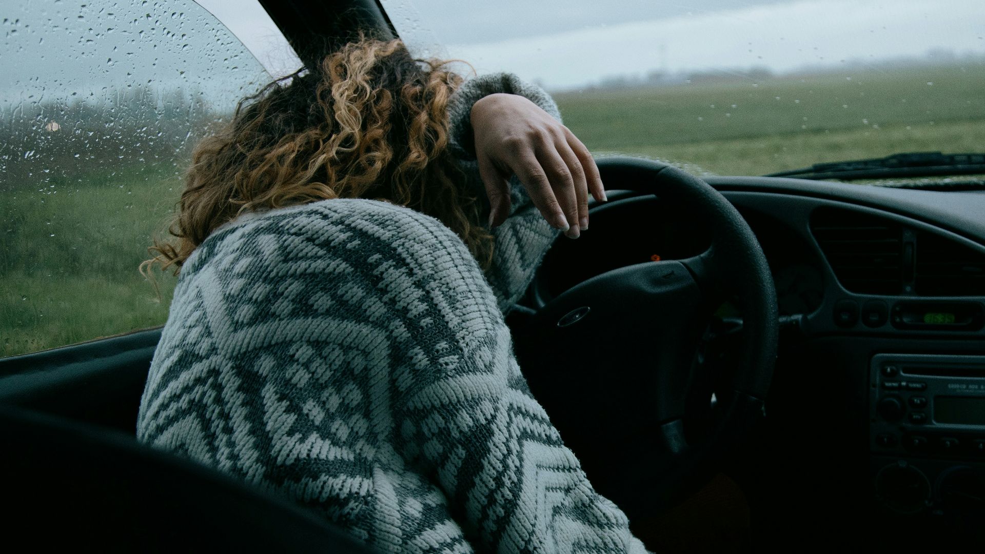 person in gray and white sweater driving car