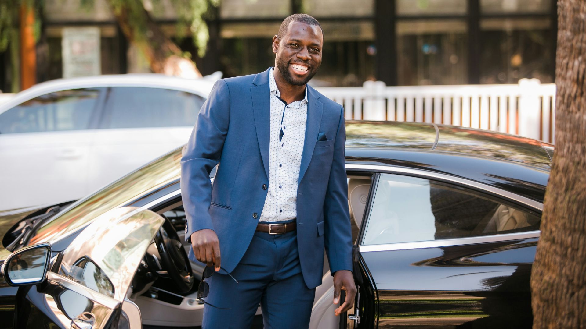 man in blue suit standing beside black car
