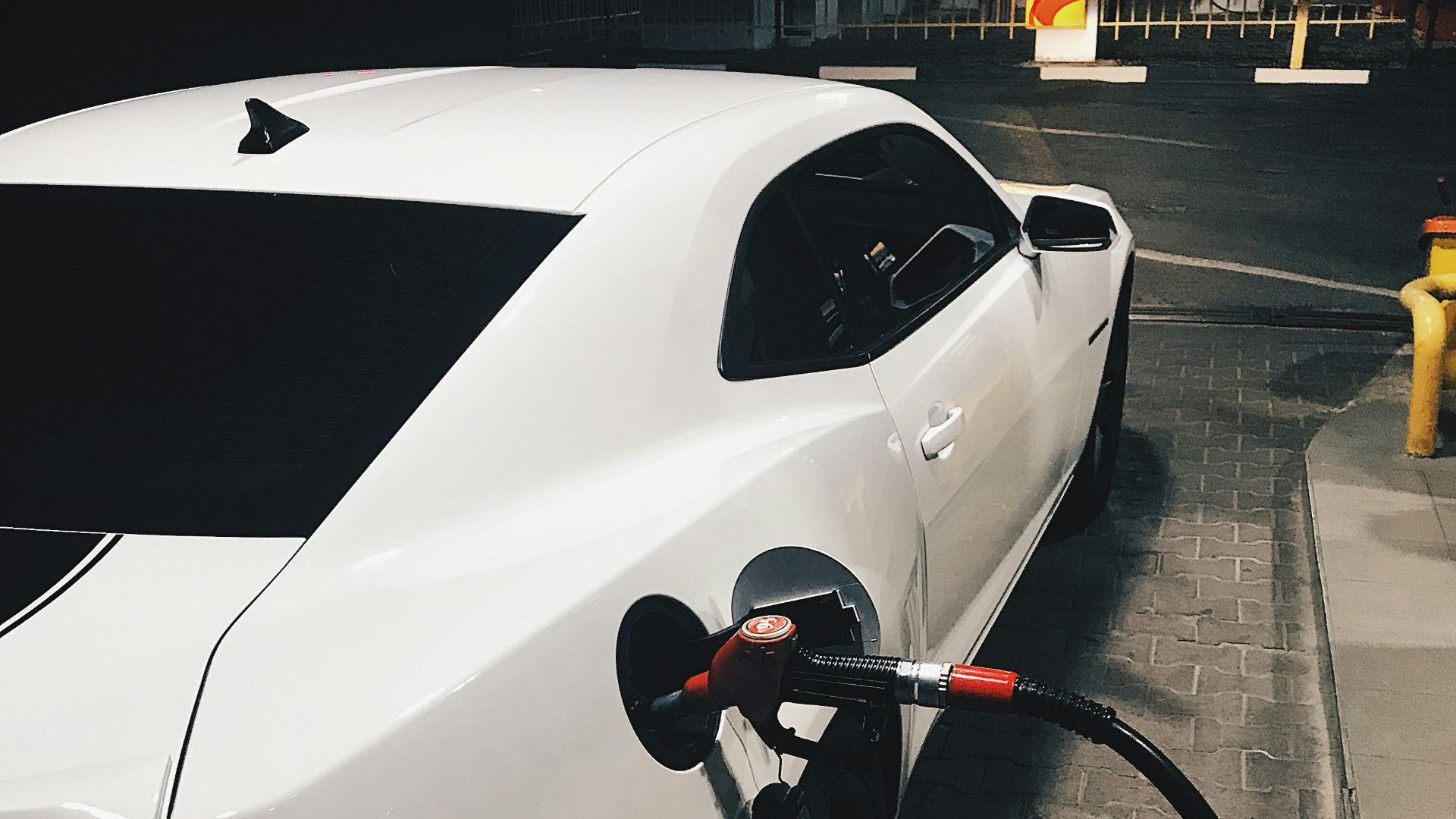 fueling white coupe at night