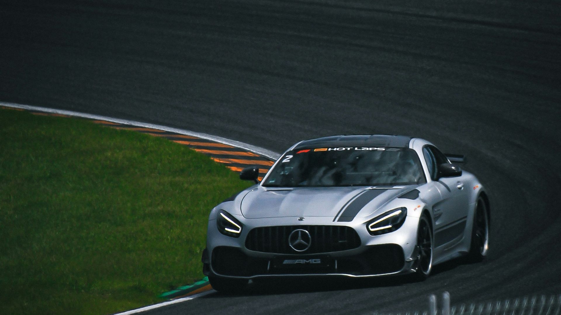 A silver sports car driving on a race track