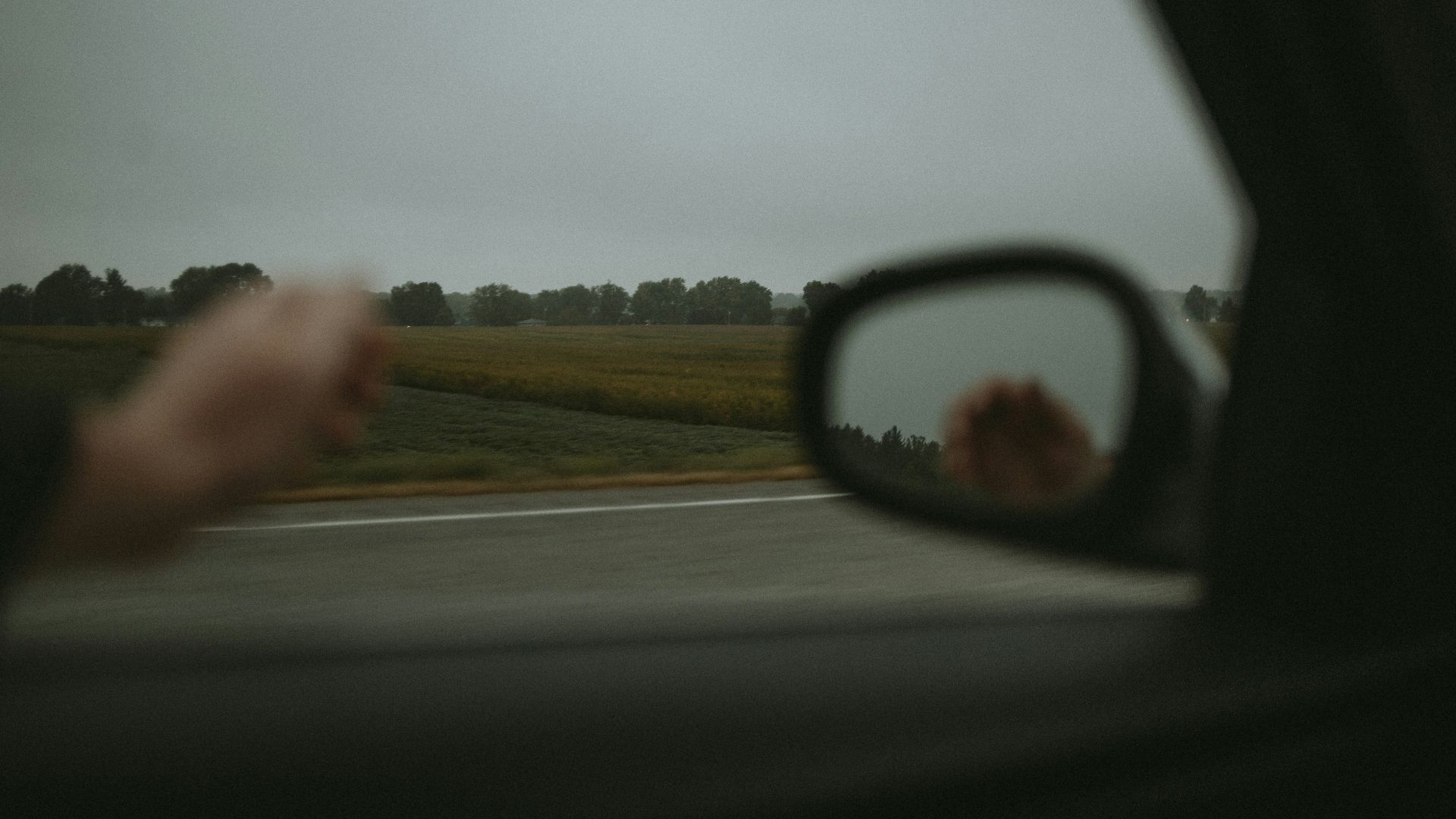 a person's reflection in the side view mirror of a car