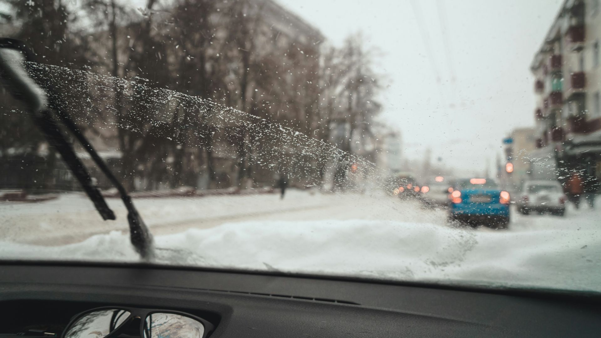 a view of a snowy street from inside a car