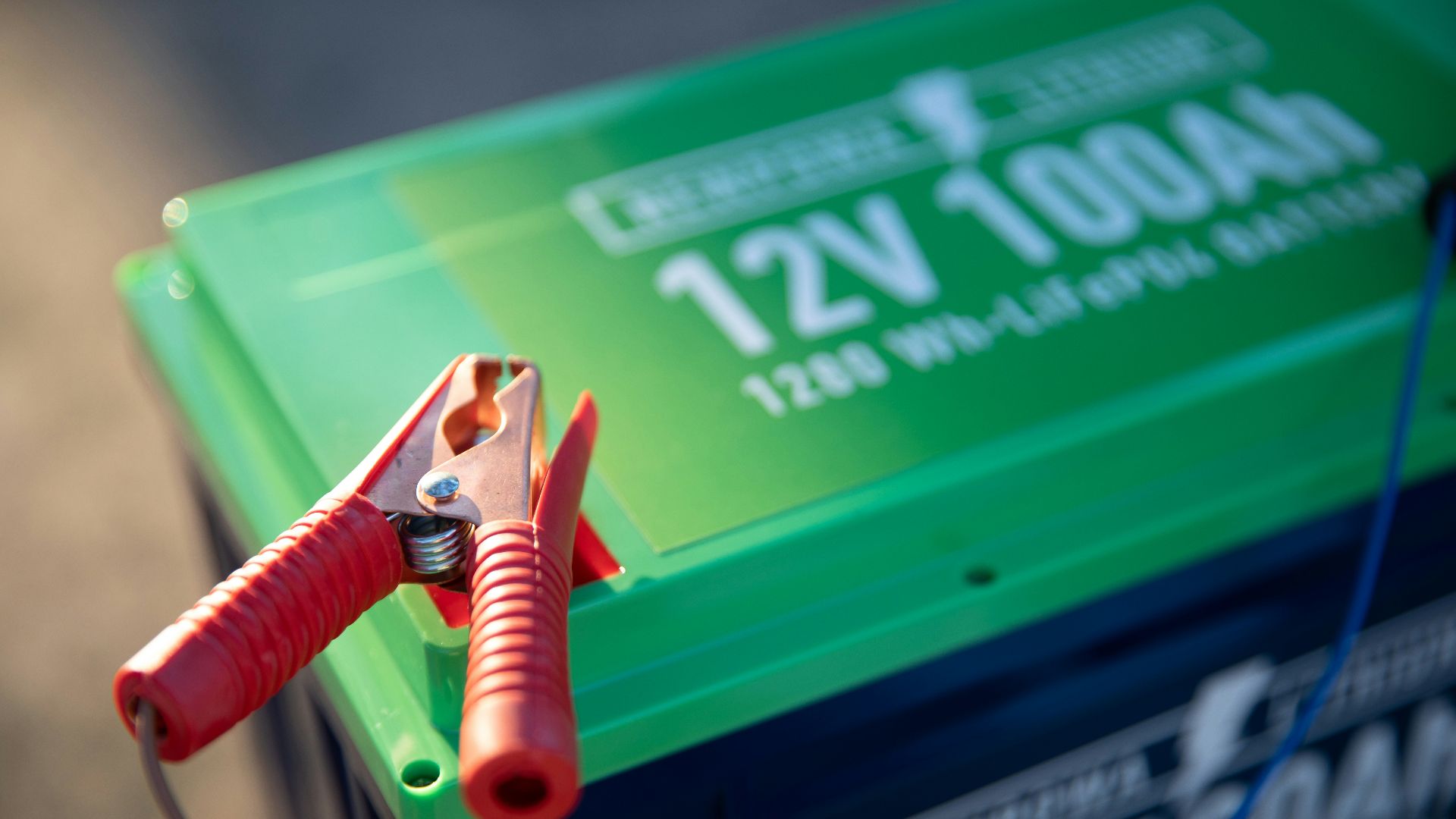 a red and green battery with a pair of pliers attached to it