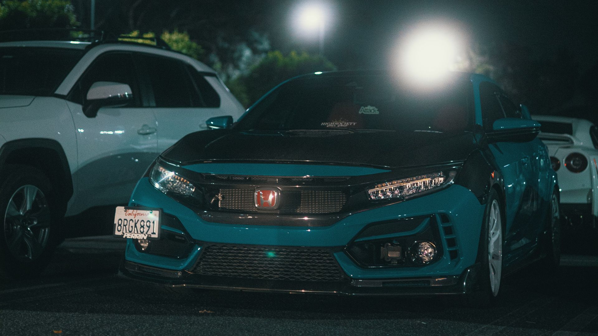 two cars parked in a parking lot at night