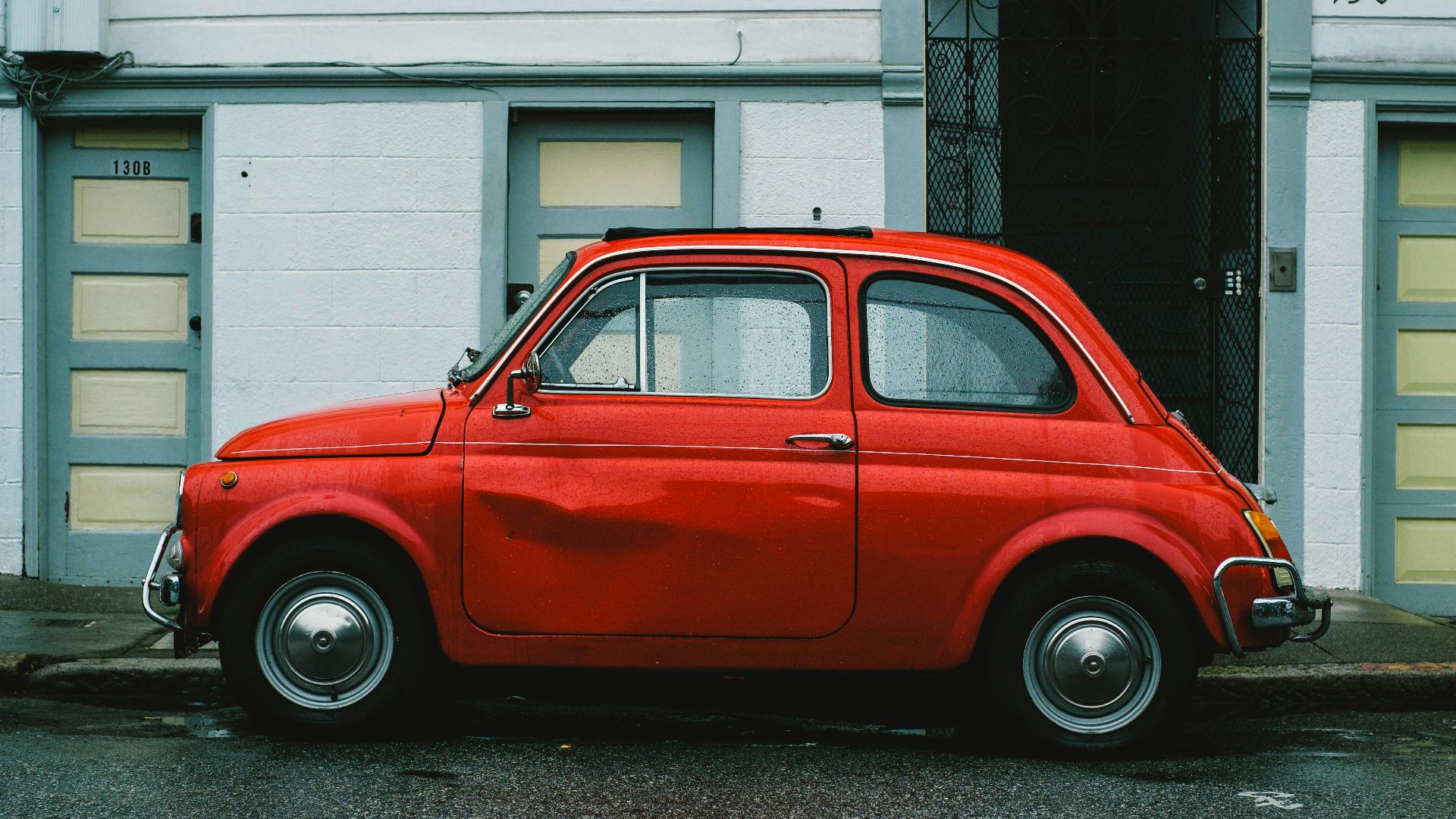 red Volkswagen Beetle car parked in front of white house