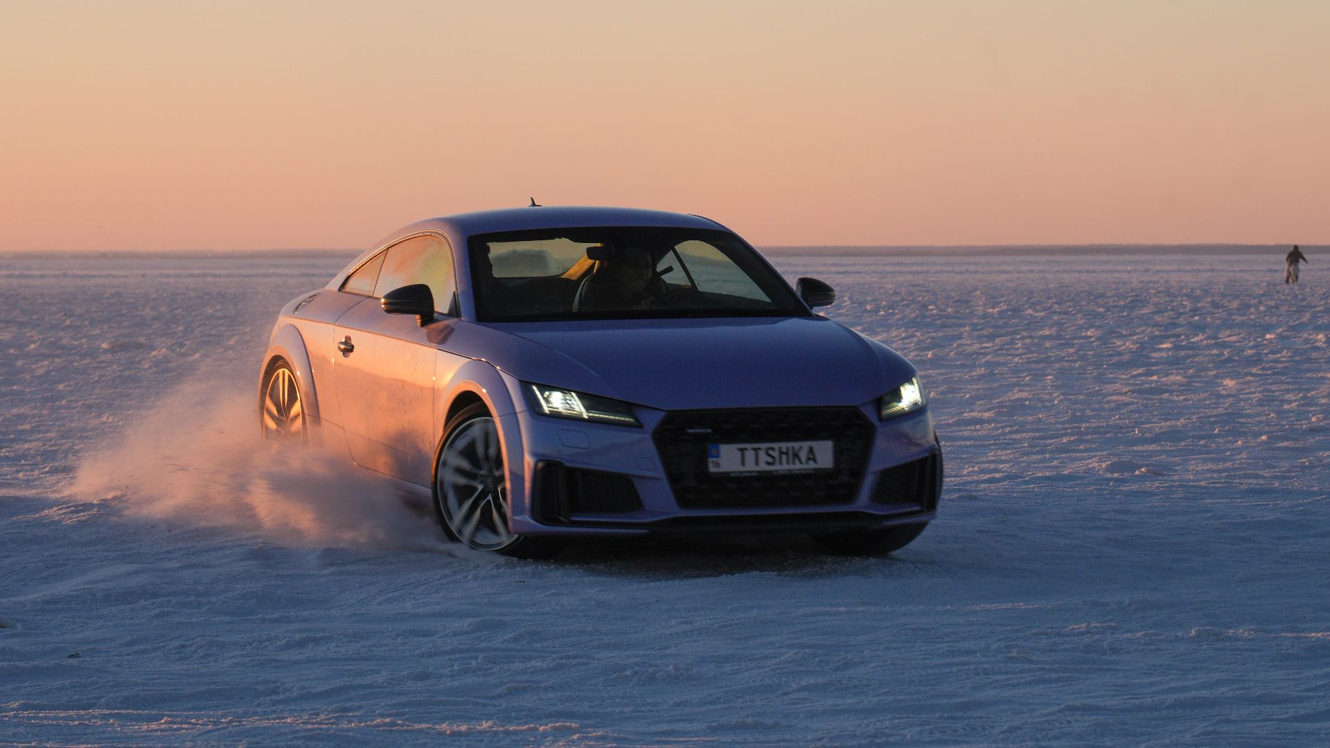 A purple car drifts on a vast, snow-covered plain.