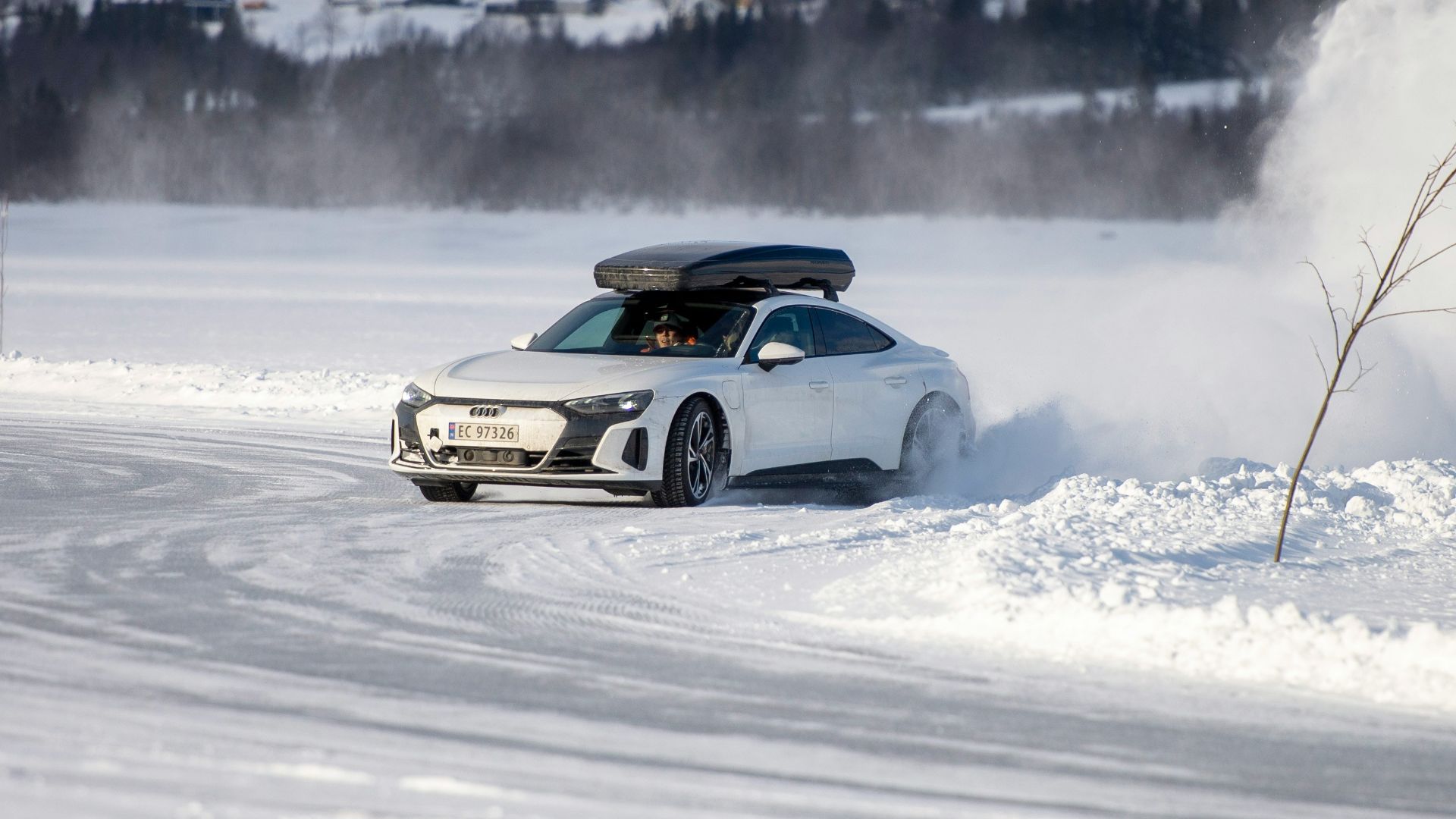 a white car driving down a snow covered road