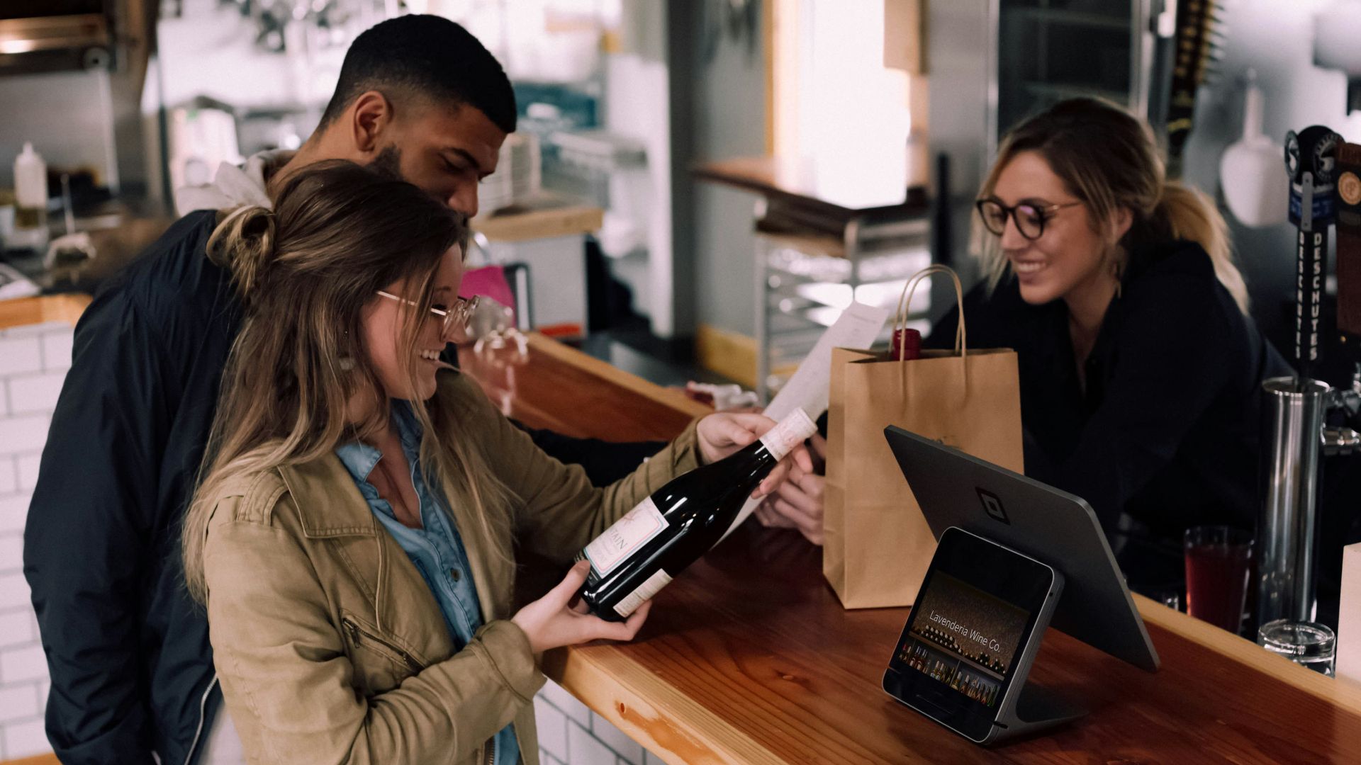 woman holding wine bottle beside man in front of woman smiling