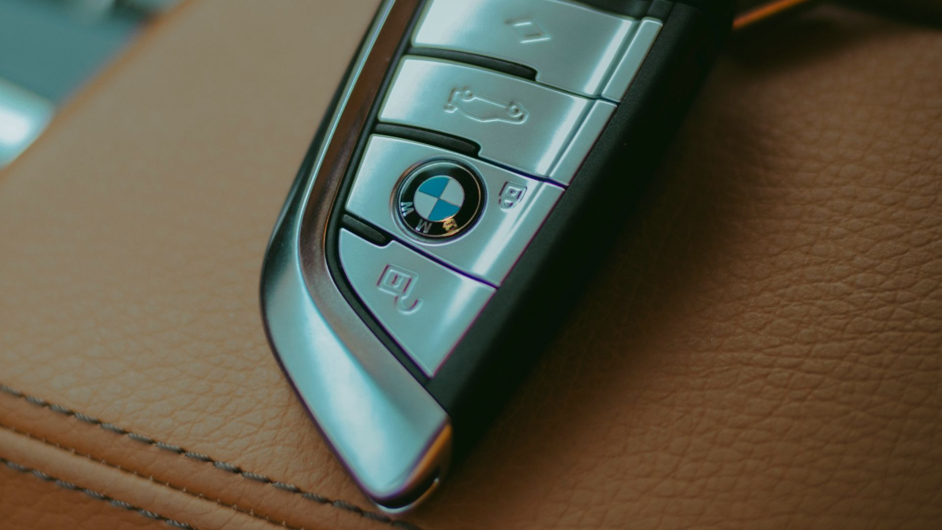 Two BMW car keys resting on leather seats.