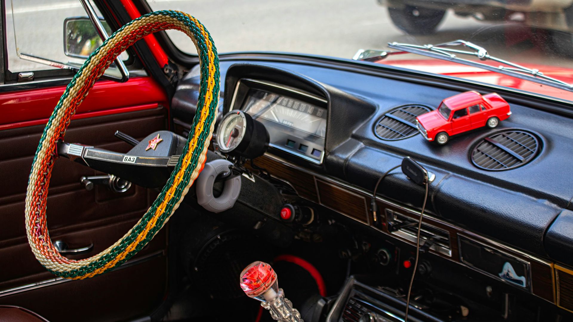 Red toy car on a vintage car dashboard