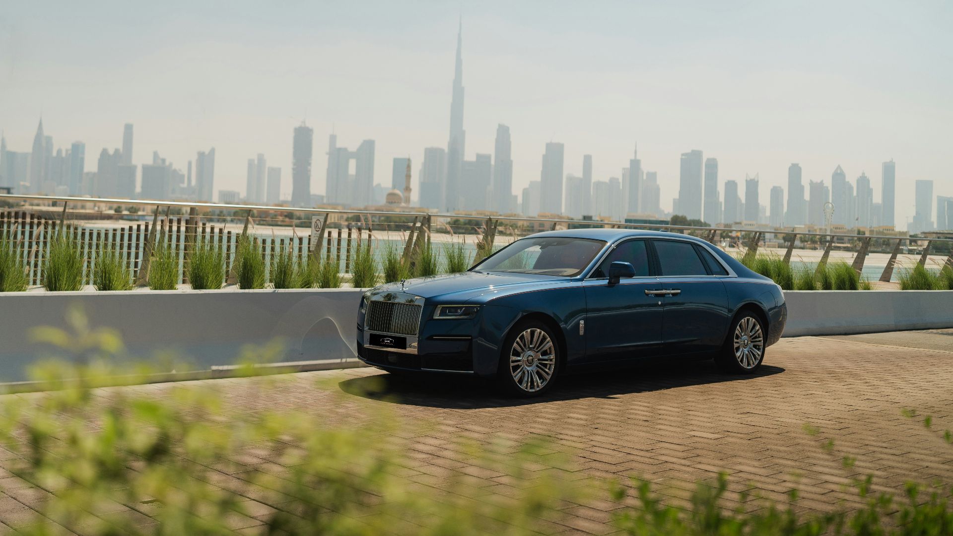 A blue car driving down a road in front of a city